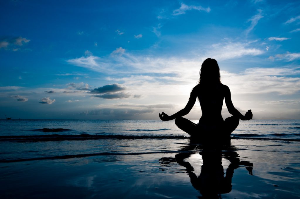 Mujer meditando en la playa